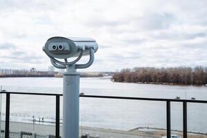 Coinoperated binoculars located on a scenic balcony give visitors a breathtaking view of a wide river, enabling users to appreciate the magnificent landscape in detail and up close photo
