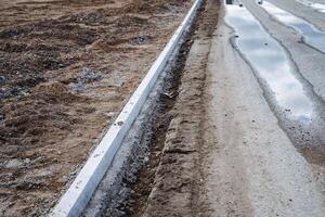 A highly durable concrete curb is currently being installed along a road in order to clearly define the designated space and significantly enhance the overall visual appearance of the area photo