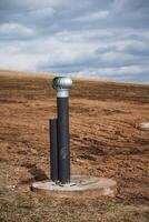 A long pipe is positioned right in the center of a sprawling dirt field, surrounded by barren land, just sitting there quietly without any movement or activity around it photo
