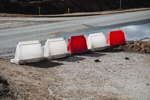 A distinct and noticeable row of red and white barriers positioned strategically on the side of a busy road, ensuring safety and guiding traffic effectively along the highway photo