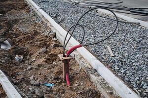 A bunch of various wires are protruding from the ground, jumbled together and creating an interesting yet chaotic sight. They appear to be part of an installation or project nearby photo