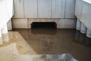 The image depicts a flooded tunnel, featuring water accumulation with a drain visibly emerging from it, providing an interesting view of the infrastructures water management system photo