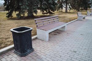 There is a lovely park that features a comfortable bench for sitting and a convenient trash can for disposing of waste, making it an inviting public space for visitors and passersby photo