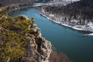 This captivating image shows an aerial view of a beautiful river flowing through a lush landscape filled with vibrant trees and rugged rocks, creating a breathtaking scene photo