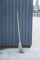 A bright, purplehandled mop is casually leaning against a wall, showcasing its vibrant color while waiting to be used for effective cleaning and maintenance in a household setting photo