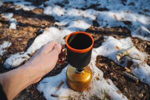 A person is standing outside in the falling snow, holding a steaming cup of freshly made coffee in their hands, trying to find a sense of warmth amidst the very cold winter day photo
