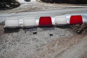 A long, continuous row of red and white barriers placed strategically along the side of a busy road, providing a visual indication of designated areas or potential hazards ahead photo