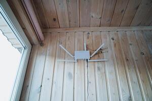 A router is securely mounted on a wooden wall that is situated right next to a large window which allows for natural light to fill the room, creating a bright and inviting atmosphere photo