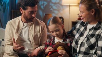 Happy European family at evening home talking parents hugging daughter talk conversation smiling relaxing on couch satisfied parents with child girl kid holding toy teddy bear adopt custody cozy rest photo