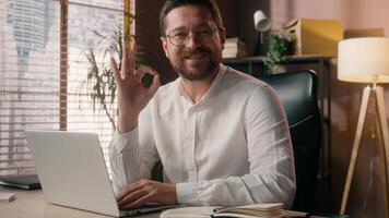 Satisfied Caucasian developer employer agent worker manager work laptop male businessman looking at camera guy trader showing okay fine gesture leader approval accept man agreeing in office business photo