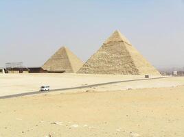 Pyramids. In the distance, the majestic pyramids of Egypt are visible against the backdrop of the endless desert and the bright blue sky photo
