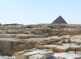Rocks. In the distance, the majestic pyramids of Egypt are visible against the backdrop of the endless desert and the bright blue sky photo