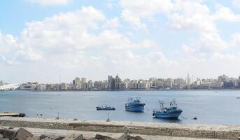 Several boats are sailing in the open sea under bright sunlight. The water is shimmering with shades of blue photo