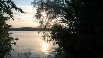 The sun is reflected in the river. A magical sunset over a river, where the last rays of the sun create a golden-pink glow on the water. photo