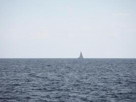The boundless expanse of the sea with gentle waves shimmering in the sunlight. In the distance, on the horizon photo