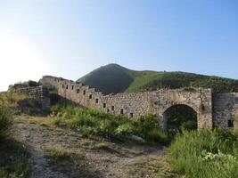 Fortress. A mighty ancient fortress stands on a rocky island surrounded by turquoise waters of the sea. Massive stone walls photo