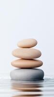 Stack of smooth stones balanced atop each other on calm water, creating ripples. The image symbolizes balance, peace, and tranquility. Perfect for wellness concepts. photo