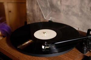 Vintage turntable with vinyl record on a wooden table. After edits. photo