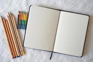 Creative beginnings month usa blank sketchbook with colorful pencils on soft fabric background photo