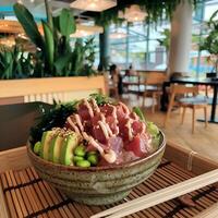 A bowl of sushi sitting on top of a wooden tray photo