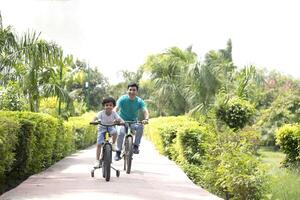 Dad And Son Ride On Bikes In the Park Road photo