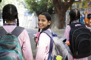 Sweet Teenagers In School Uniform With Hand On Shoulder Posing In Garden In Front Of Camera photo