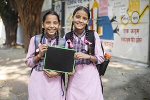 Portrait Of Cute Indian Girls Sitting And Hugging Each Other In Park While Posing In Front Of Camera photo