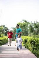 Old Man Running Behind Son And Grandson In Park photo