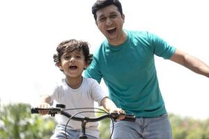Nice Kid Learning Bicycle With Assistance Of Father At Park photo