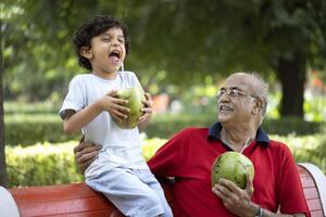 Happy Child Smiling While Drinking Tender Coconut Water With Grandpa photo