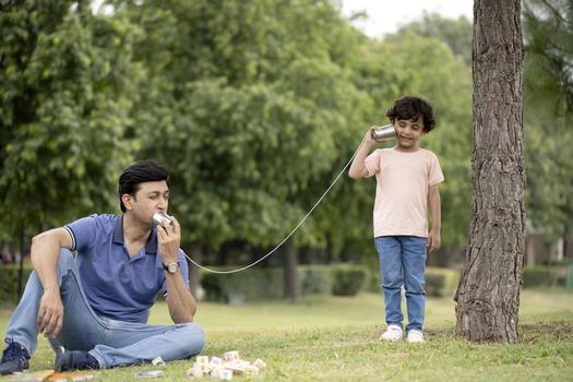 Father With Son Talking On String Telephone In Park photo