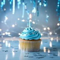 A blue cupcake with a lit candle on top photo