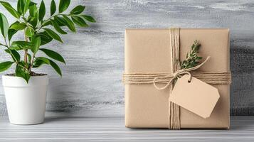 Gift wrapped in brown paper with tag and plant on wooden table photo