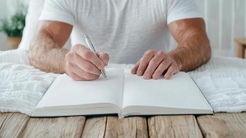 A man is writing in a notebook while sitting on a bed photo