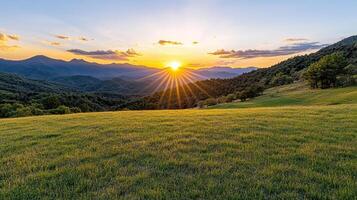 The sun setting over a grassy field in the mountains photo