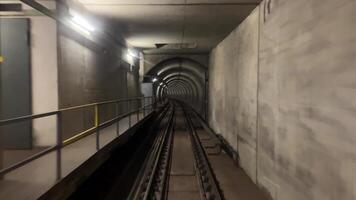 Dark underground subway tunnel with empty railway tracks stretching into the distance. Industrial lighting illuminates the concrete walls, creating a moody, mysterious atmosphere. video