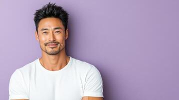 A man in a white t - shirt is standing in front of a purple wall photo