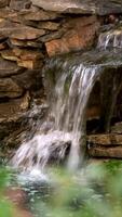 Stone wall with a waterfall in the garden. Artificial decorative waterfall from granite stone. video