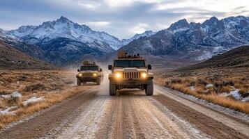 Two military vehicles driving down a dirt road in the mountains photo
