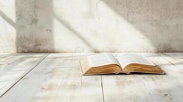 An open bible on a wooden floor in front of a wall photo