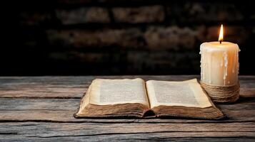 An open bible and a candle on a wooden table photo