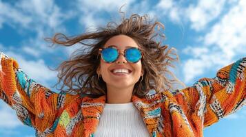 A woman in sunglasses and a colorful sweater is smiling photo