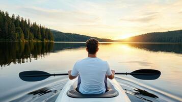 A man paddling a kayak on a lake at sunset photo
