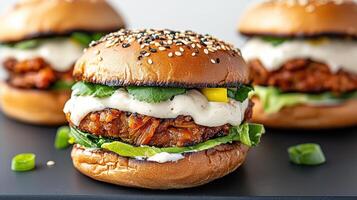Three burgers with toppings on a black plate photo