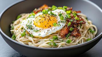A bowl of noodles with bacon and an egg photo