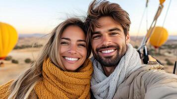 A man and woman taking a selfie in front of a hot air balloon photo