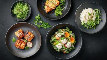 Four plates with food on them, including a salad, rice and chicken photo