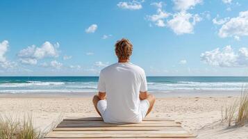 A man sitting on a wooden boardwalk at the beach photo
