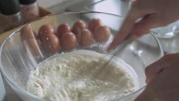 Hand using metal whisk to mix pancake batter in glass bowl video