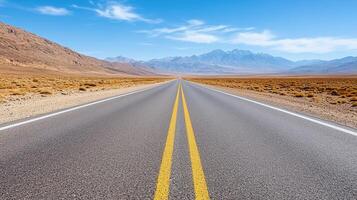 A long empty road in the desert with mountains in the background photo